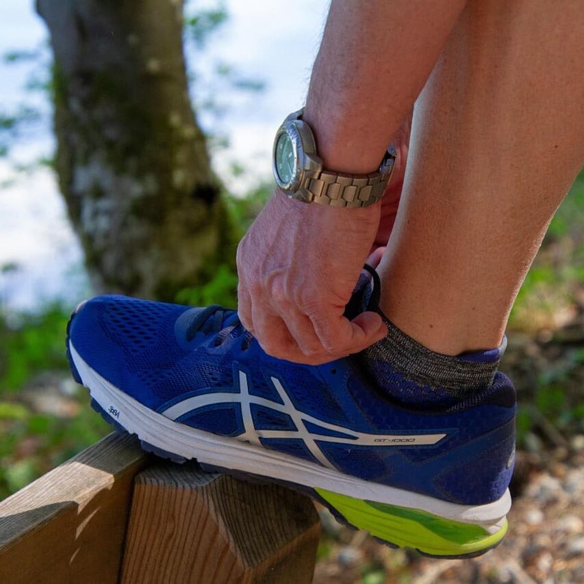 sports-3340598_1280 Runner ties shoe while stretching.